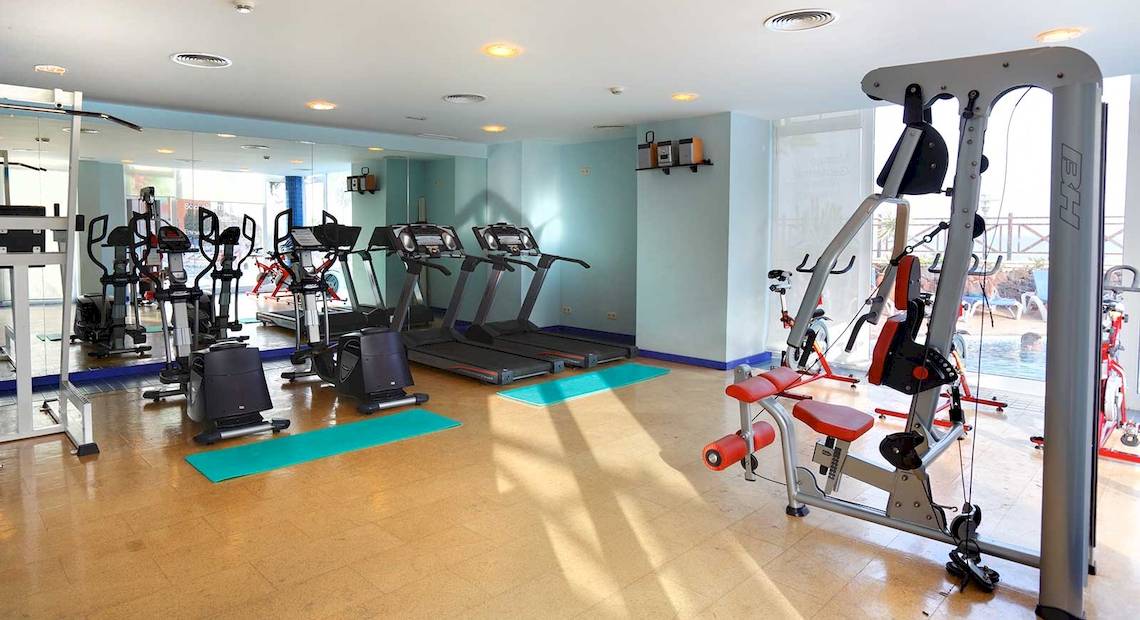 Fitnessstudio im Occidental Jandia Playa Hotel mit diversen Geräten und Spiegeln.