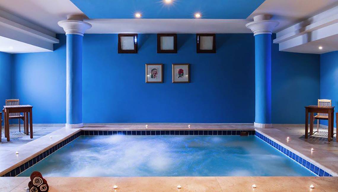 Ein blauer Innenpool des Jaz Lamaya Resorts mit Tisch und Stühlen.