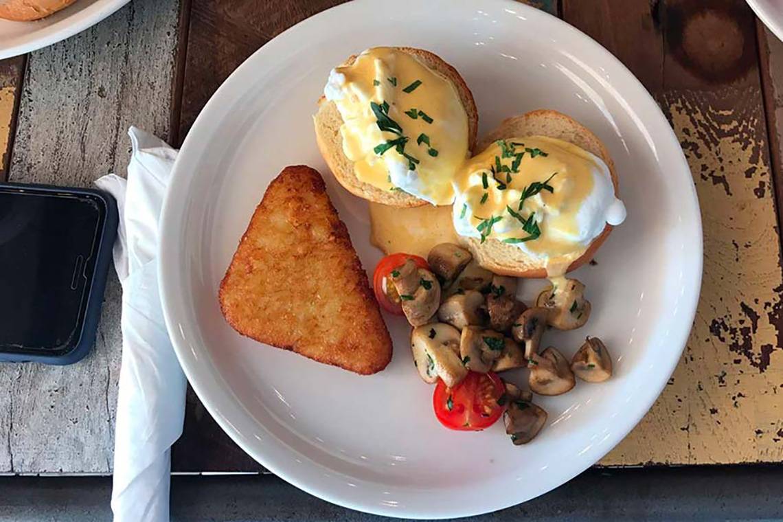 Frühstücksplatte mit Eier Benedict, Pilzen, Tomaten und einem gebratenen Stück Brot.