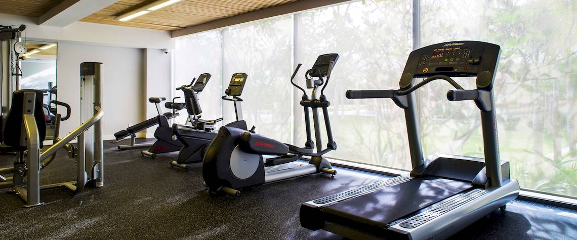 Fitnessstudio im Salinda Resort auf Phu Quoc Island mit mehreren Trainingsgeräten und großen Fenstern.