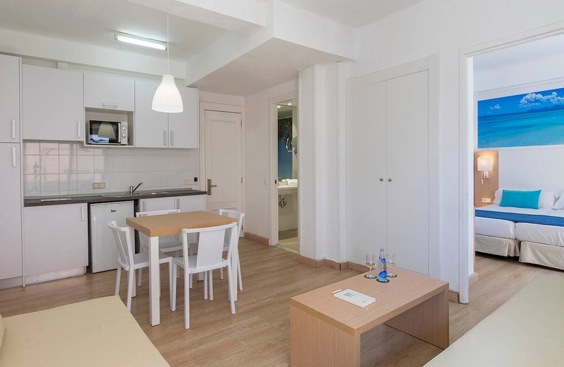 Innenansicht des Whala Beach Hotel Zimmers mit Küchenzeile, Esstisch, Sofa und Schlafzimmerbereich.