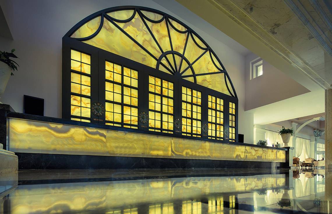 Empfangsbereich des Titanic Deluxe Golf Belek Hotels mit großem Fenster und gelben Marmor.