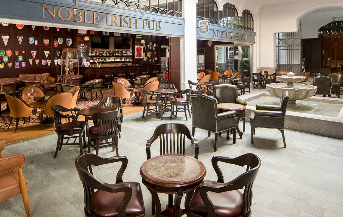 Innenansicht des Noble Irish Pub mit Lederstühlen, Tischen und einer Bar.