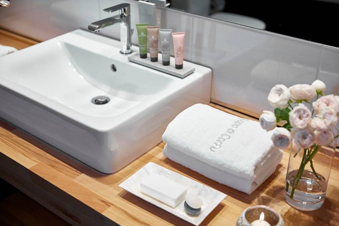 Badezimmer im Capo Di Corfu Hotel mit Waschbecken, Handtüchern und Pflegeprodukten.