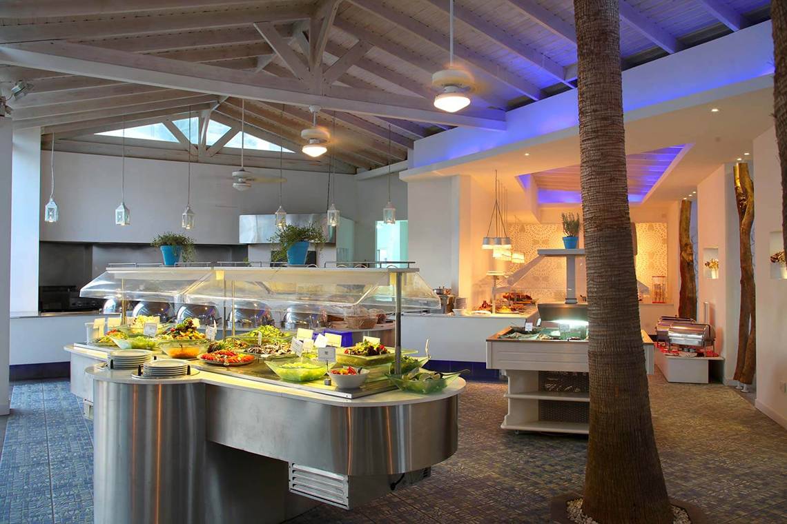 Buffetbereich im GrandResort Limassol mit verschiedenen Speisen und einer Palme.