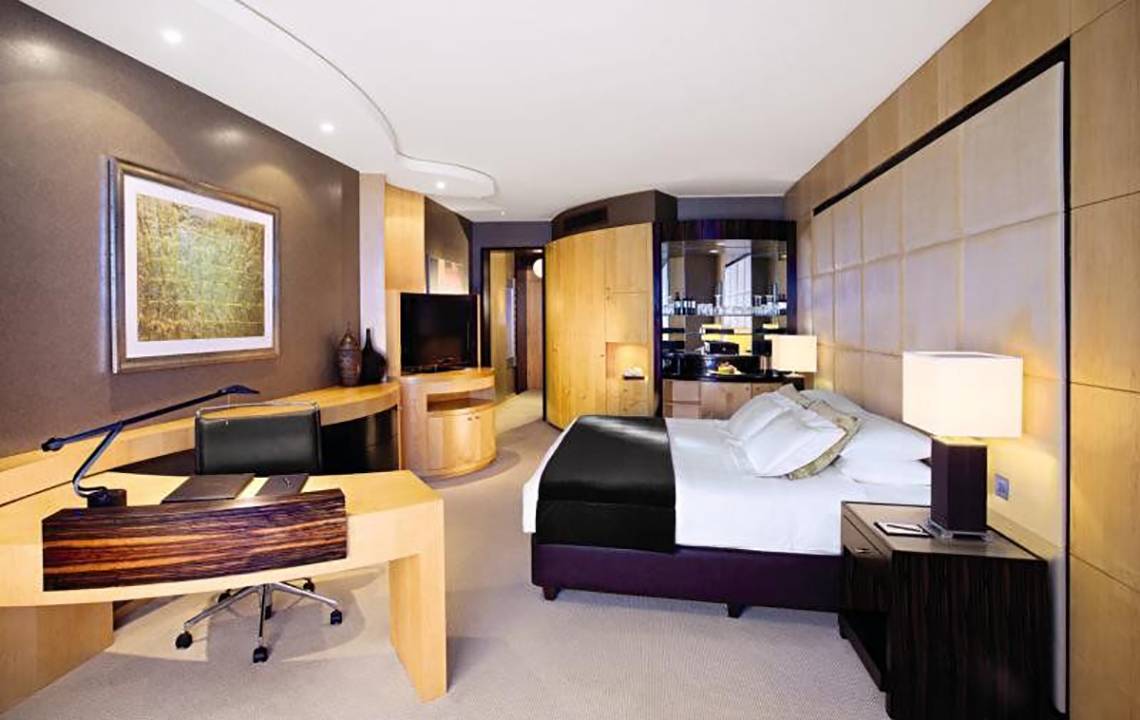 Luxuriöses Hotelzimmer im Shangri-La Dubai mit Schreibtisch, Bett und Fernseher.