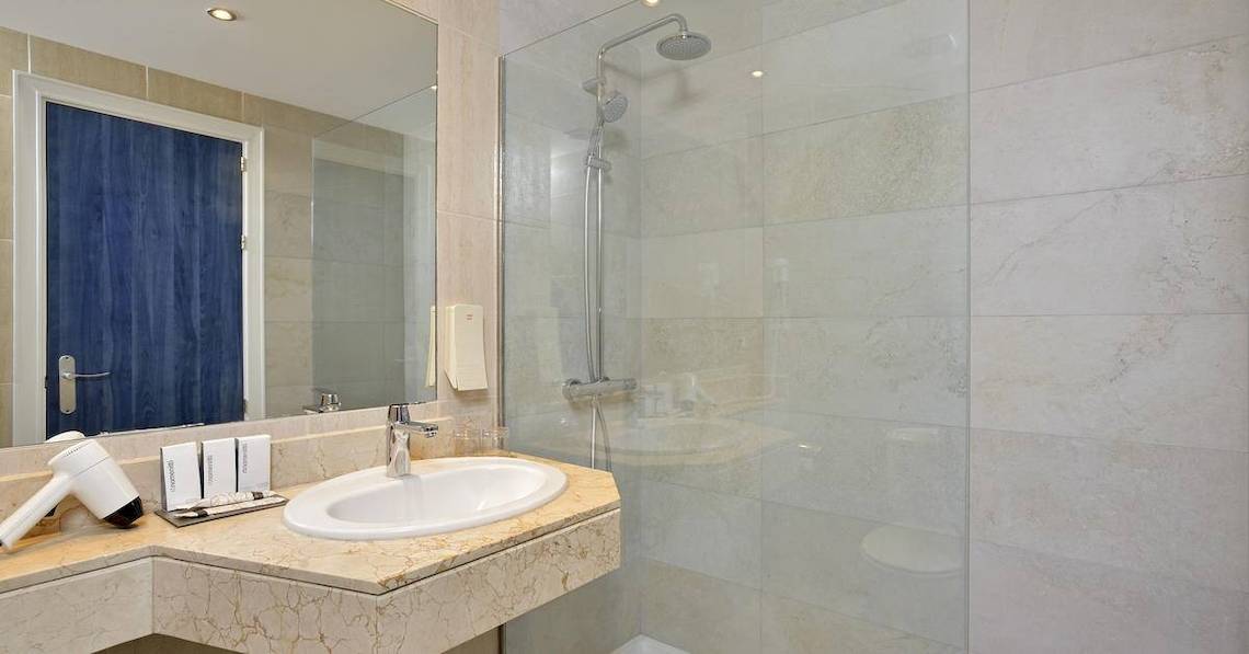 Badezimmer im Sol Guadalupe Hotel mit großer Dusche, Waschbecken und Spiegel.