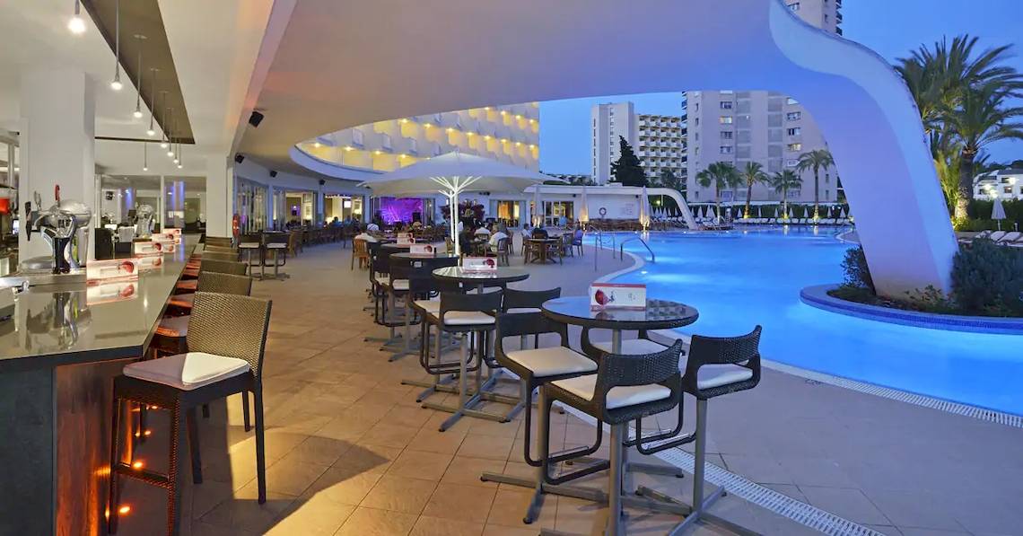 Pool-Lounge im Sol Guadalupe Hotel mit Tischen, Stühlen und beleuchtetem Pool