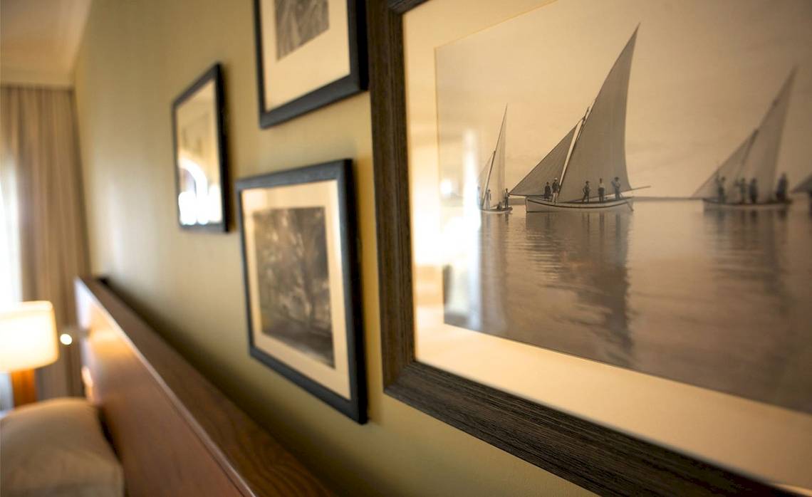 Ein Hotelzimmer mit drei gerahmten Bildern an der Wand, die Segelboote auf dem Wasser darstellen.