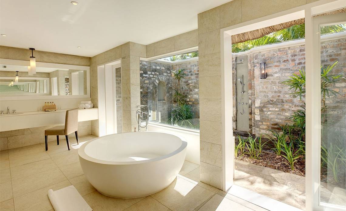 Badezimmer im Outrigger Mauritius Beach Resort mit Badewanne und Außendusche.
