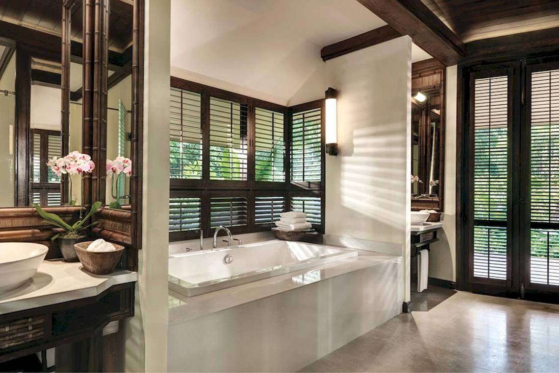 Ein Badezimmer im Rayavadee Hotel mit einer Badewanne, zwei Waschbecken, und großen Fenstern mit Jalousien.