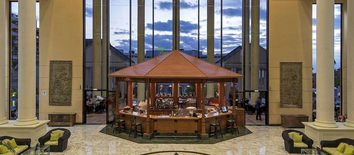 Lobby des Princess Inspire Tenerife Hotels mit Pavillon und Bar, umgeben von Säulen und Möbeln.