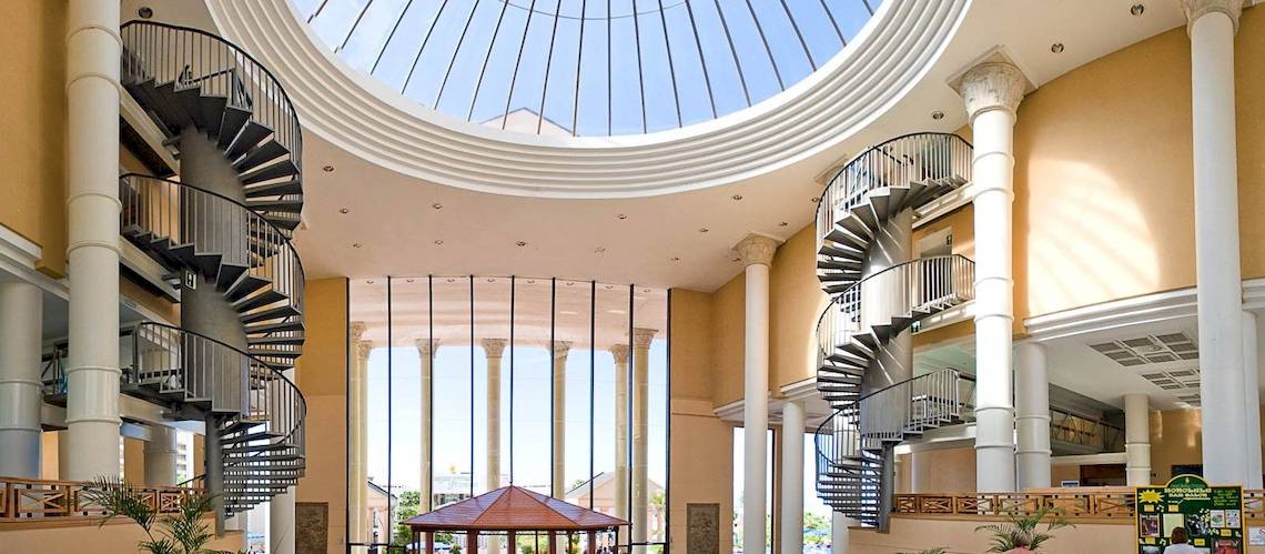Innenansicht des Princess Inspire Tenerife Hotels mit zwei spiralförmigen Treppen und einer Glaskuppel.
