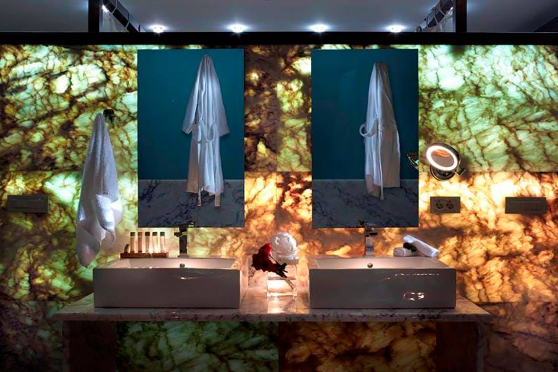 Badezimmer im Royal Blue Resort mit zwei Waschbecken und Spiegeln an einer Marmorwand.