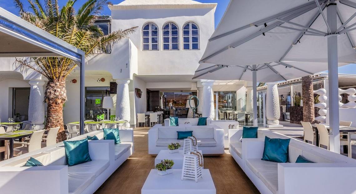 Außenbereich des Barcelo Fuerteventura Castillo Hotels mit weißen Sofas, Tischen und Palmen