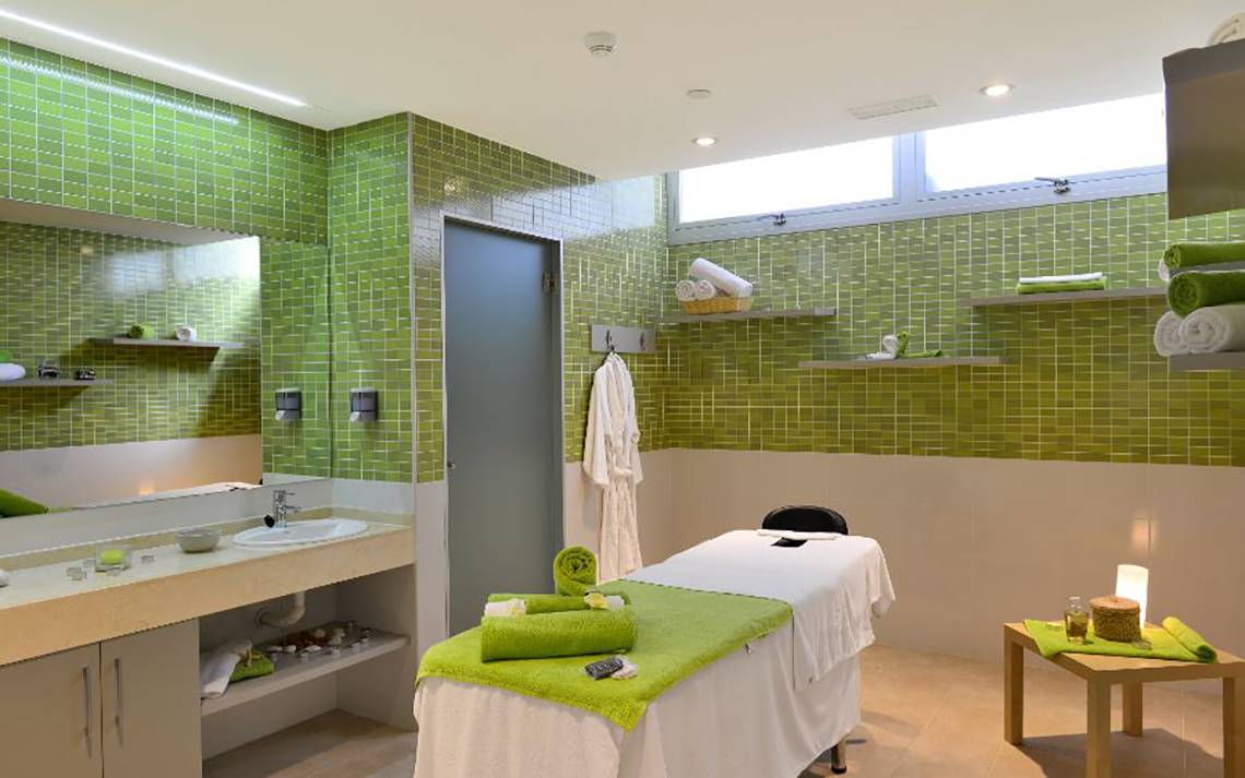 Massage-Behandlungsraum im Alexandre Hotel Troya mit grünen Fliesen und einer Liege.