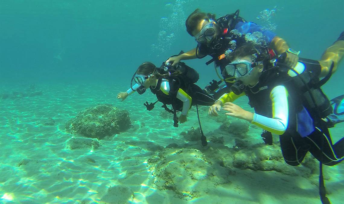 Drei Taucher erkunden das Meer bei Candia Park Village.