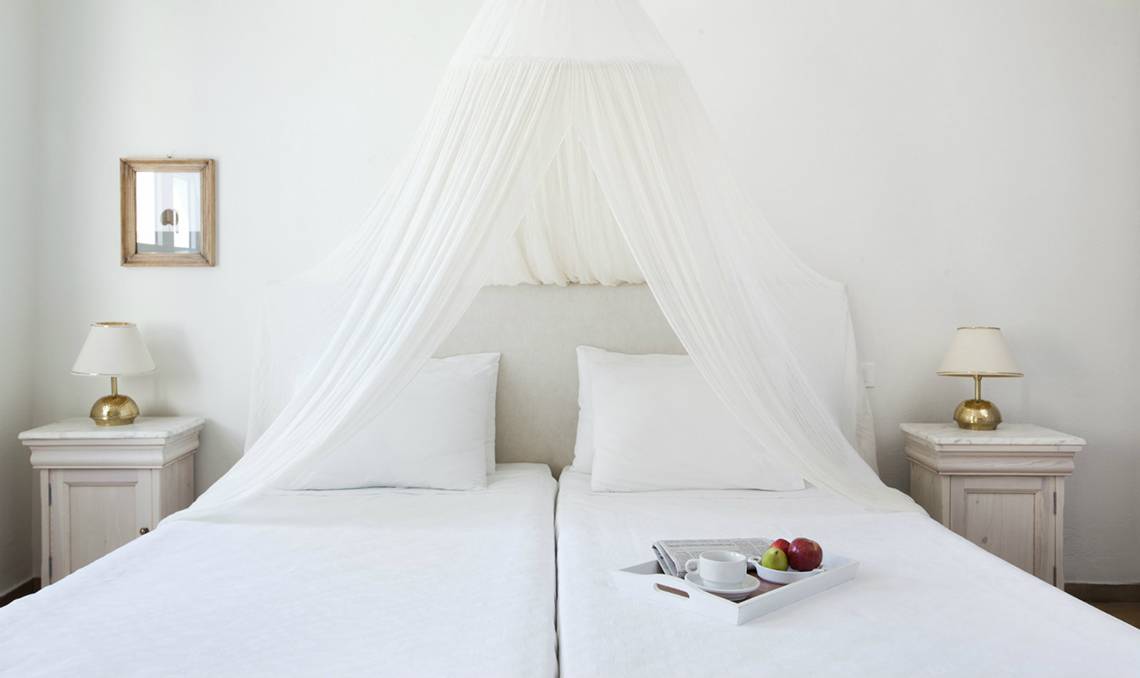Doppelbett mit Baldachin im Candia Park Village Hotel, Früchte und Kaffee auf dem Bett.