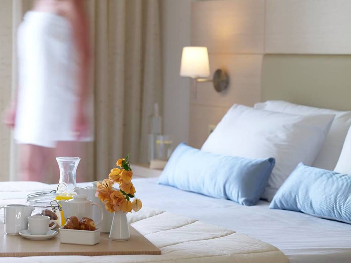 Frühstückstisch im Hotelzimmer von Porto Bello Beach mit Blumen, Kaffee und Croissants.