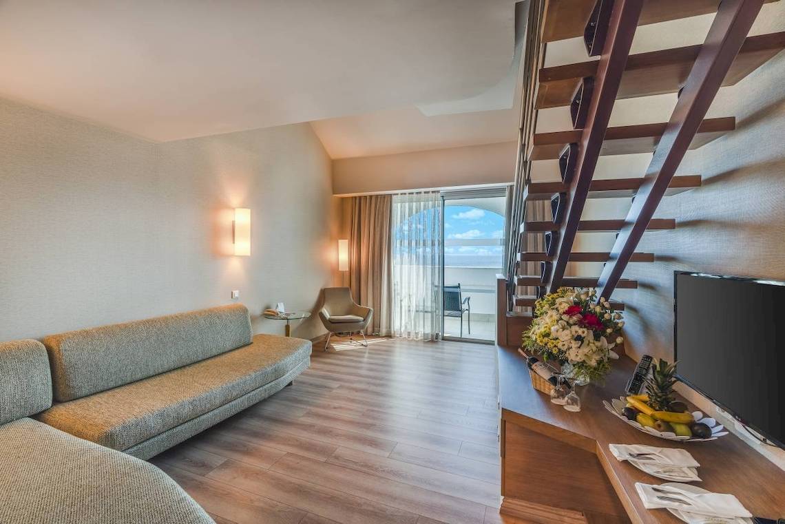 Innenraum des Concorde De Luxe Resorts mit Sofa, Tisch und Fernseher.