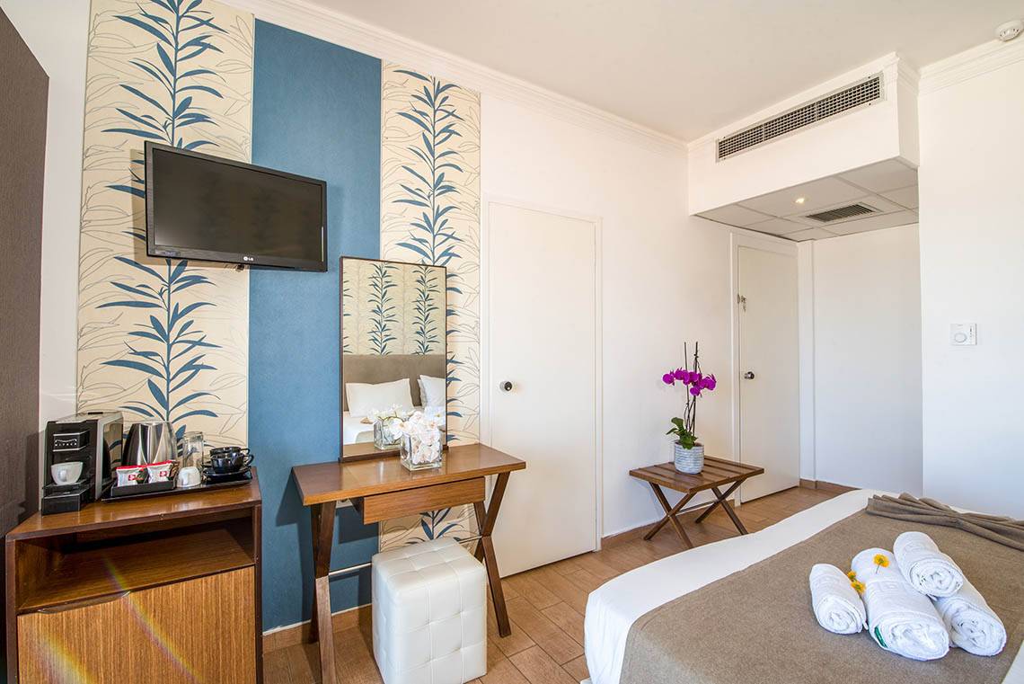 Innenansicht eines Zimmers im Kalyves Beach Hotel mit Bett, Fernseher und Dekor.