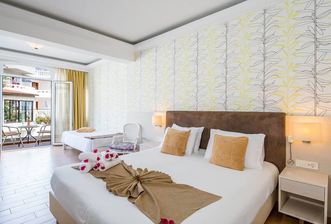 Schlafzimmer im Kalyves Beach Hotel mit zwei Betten, Dekor und Aussicht durch eine Terrassentür.