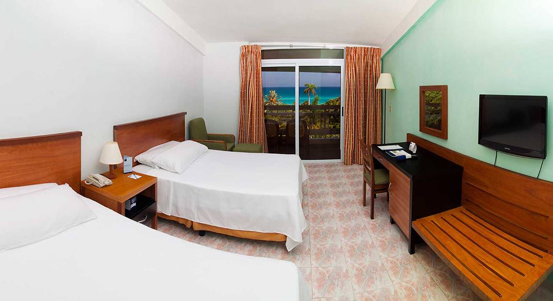 Doppelzimmer mit Meerblick im Hotel Occidental Arenas Blancas mit zwei Betten, Schreibtisch, Fernseher und Balkon.