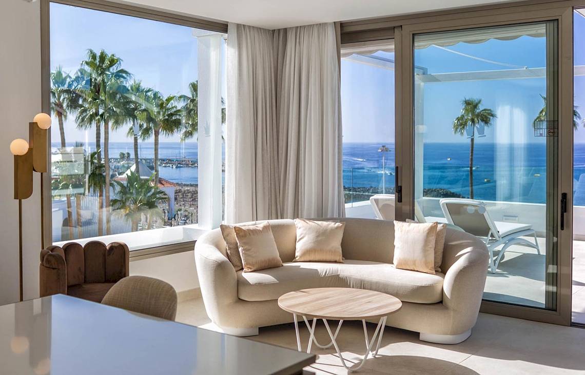 Wohnzimmer im Guayarmina Princess Hotel mit großer Fensterfront und Meerblick.