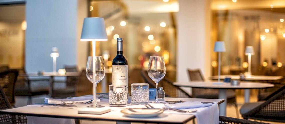 Tisch im Restaurant des Guayarmina Princess Hotels, eingerichtet mit Weinflasche, Gläsern und Besteck.