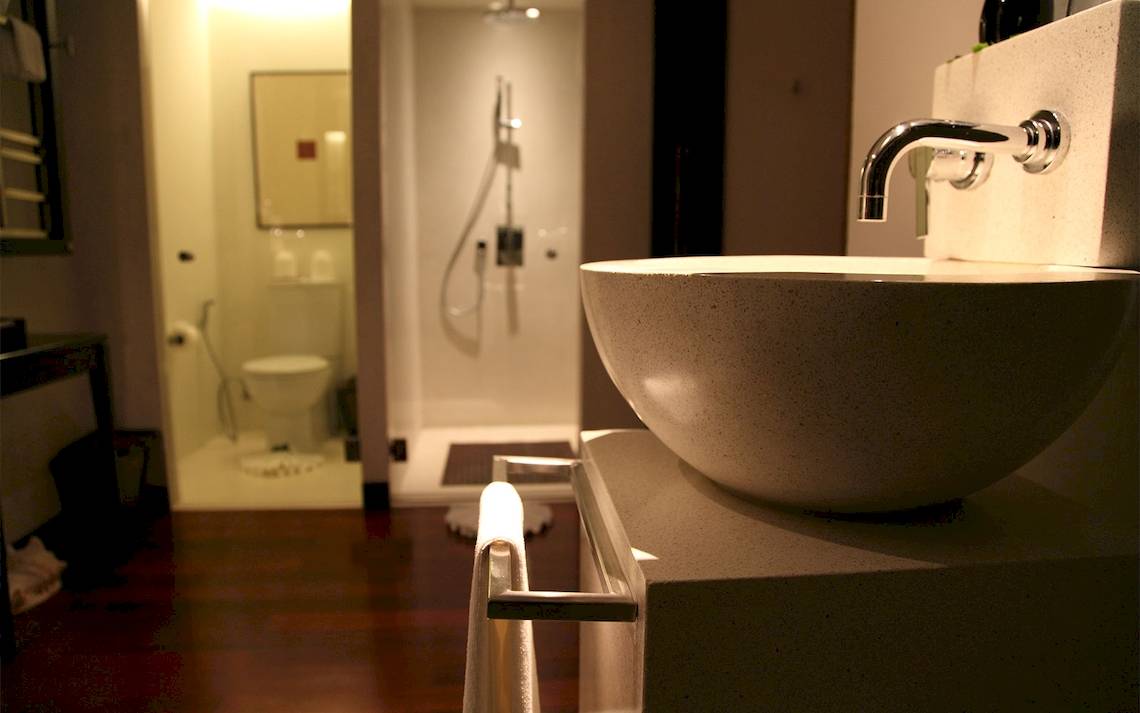 Ein Badezimmer mit einer Dusche und einem Waschbecken, das an einer Wand befestigt ist.