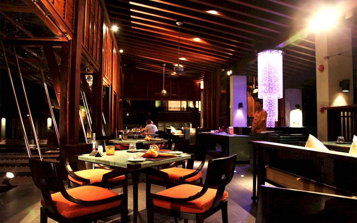 Innenbereich des Restaurants im Mai Samui Beach Resort mit gedimmten Lichtern und einem zentralen Wasserfall-Licht