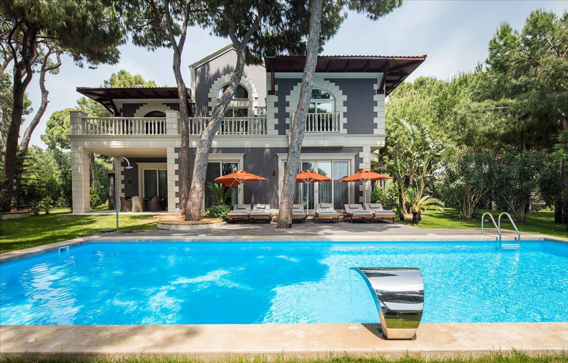 Maxx Royal Belek Golf Resort Villa mit großem Pool und Sonnenschirmen.