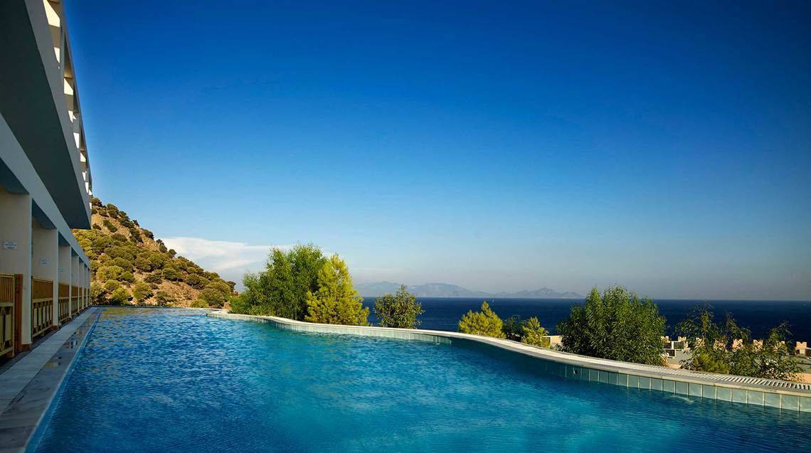 Außenpool mit Blick auf das Meer und die Berge im Mitsis Family Village Beach Hotel.