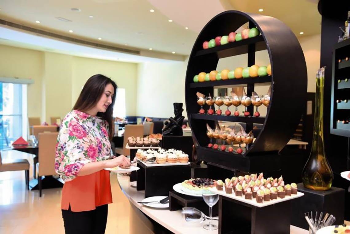 Frau serviert Desserts im Al Hamra Residence Hotel.