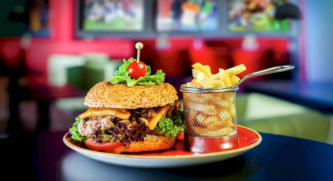 Ein Burger mit Salat, Tomaten und Pommes in einem Restaurant serviert.