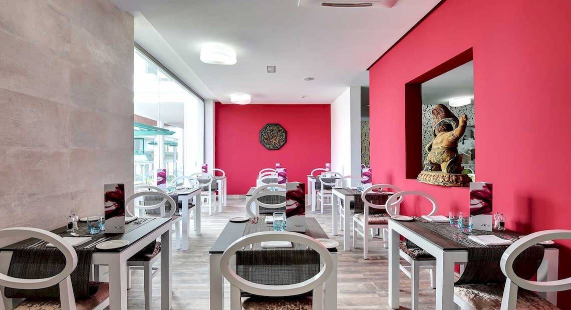 Restaurantbereich im Barceló Teguise Beach Adults Only Hotel mit roten Wänden und weißen Tischen.