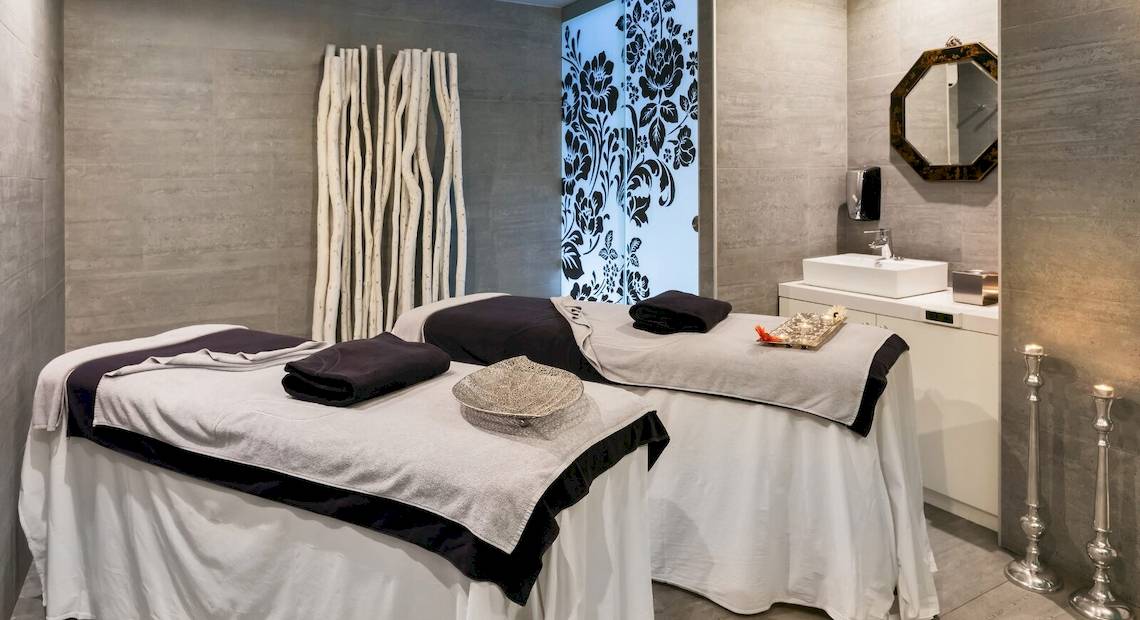 Spa-Behandlungsraum im Barceló Teguise Beach Adults Only Hotel mit zwei Massagetischen und einem Waschbecken.