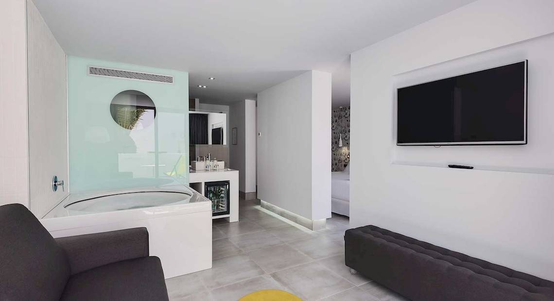 Innenansicht der Suite im Barceló Teguise Beach Hotel mit Badewanne, Fernseher und Möbeln.