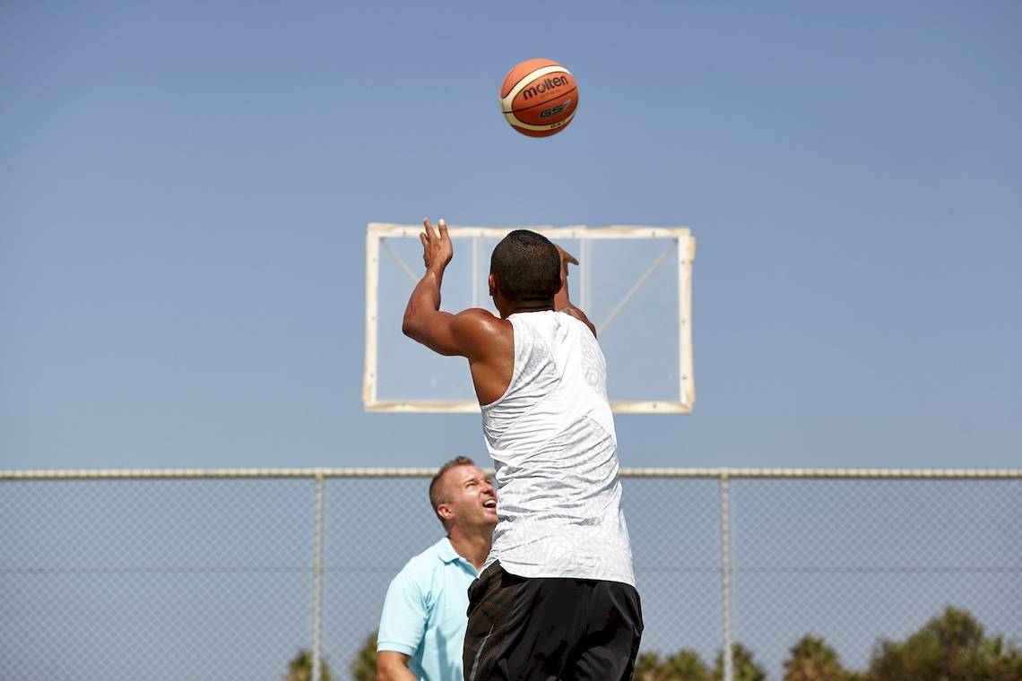 Mann wirft einen Basketball in den Korb auf einem Spielfeld