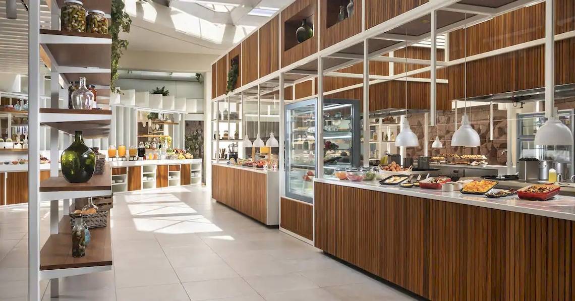 Frühstücksbereich des Melia Salinas Hotels mit Frühstücksbuffet und Holzmöbeln.