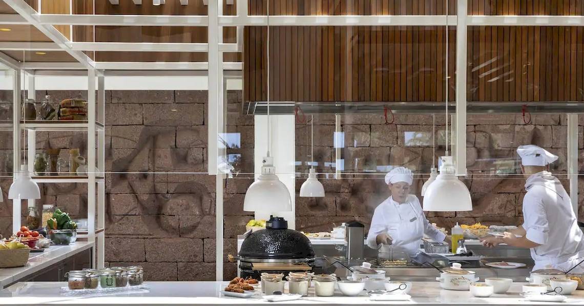 Küche des Melia Salinas Hotels mit Köchen, die Essen zubereiten und verschiedene Gerichte servieren.