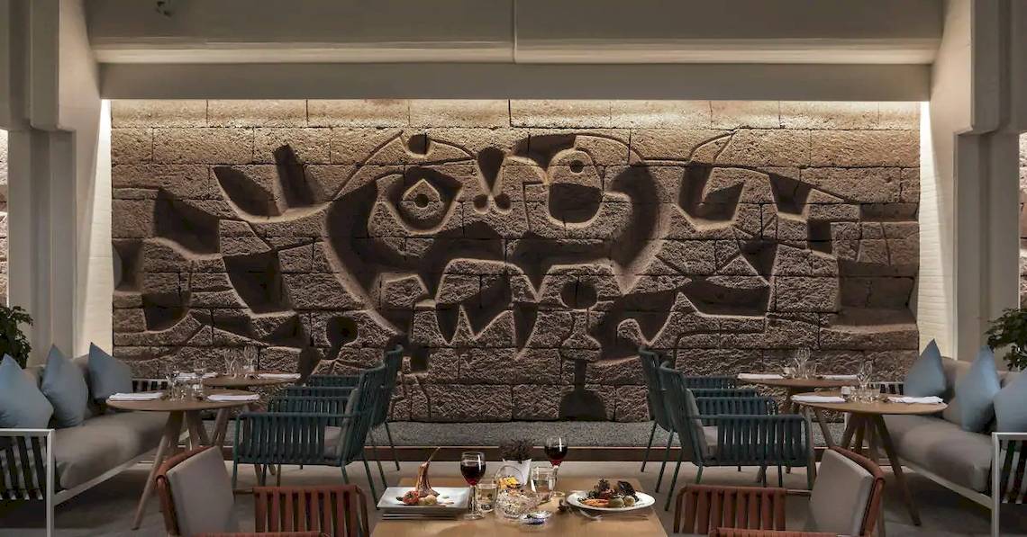 Inneneinrichtung des Melia Salinas Hotels mit einem großen Wandbild und runden Tischen.