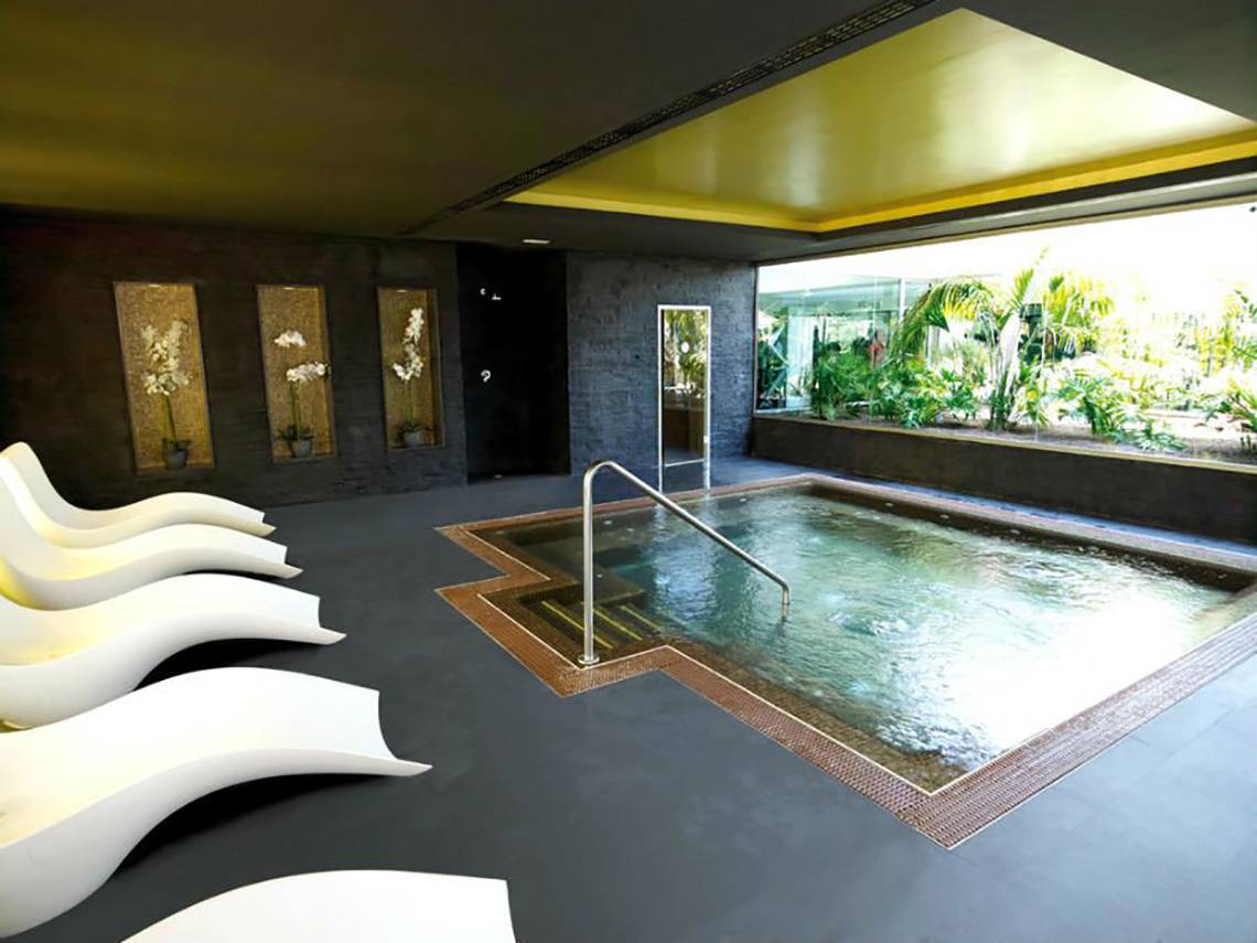 Innenpool im Riu Gran Canaria Hotel mit weißen Liegestühlen und Pflanzen im Hintergrund