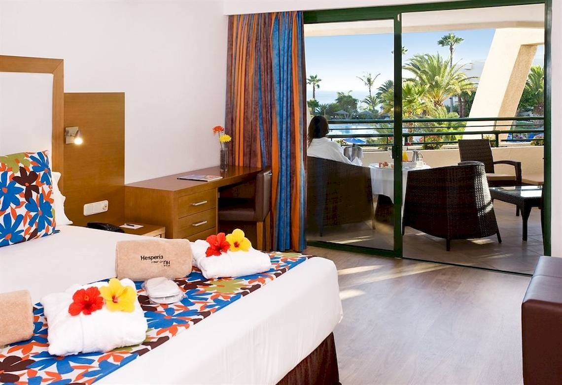 Zimmer im Dreams Lanzarote Playa Dorada Resort & Spa mit Blick auf einen Pool und Palmen.