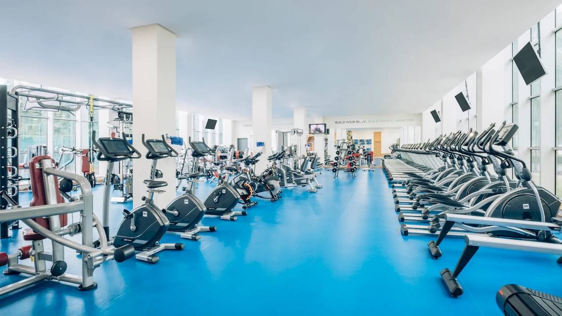 Fitnessstudio im Iberostar Grand Paraiso Hotel mit vielen Cardiogeräten und blauen Boden