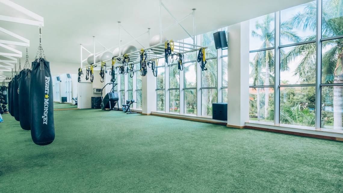 Fitnessstudio im Iberostar Grand Paraiso Hotel mit Blick auf Palmen und Außenbereich.