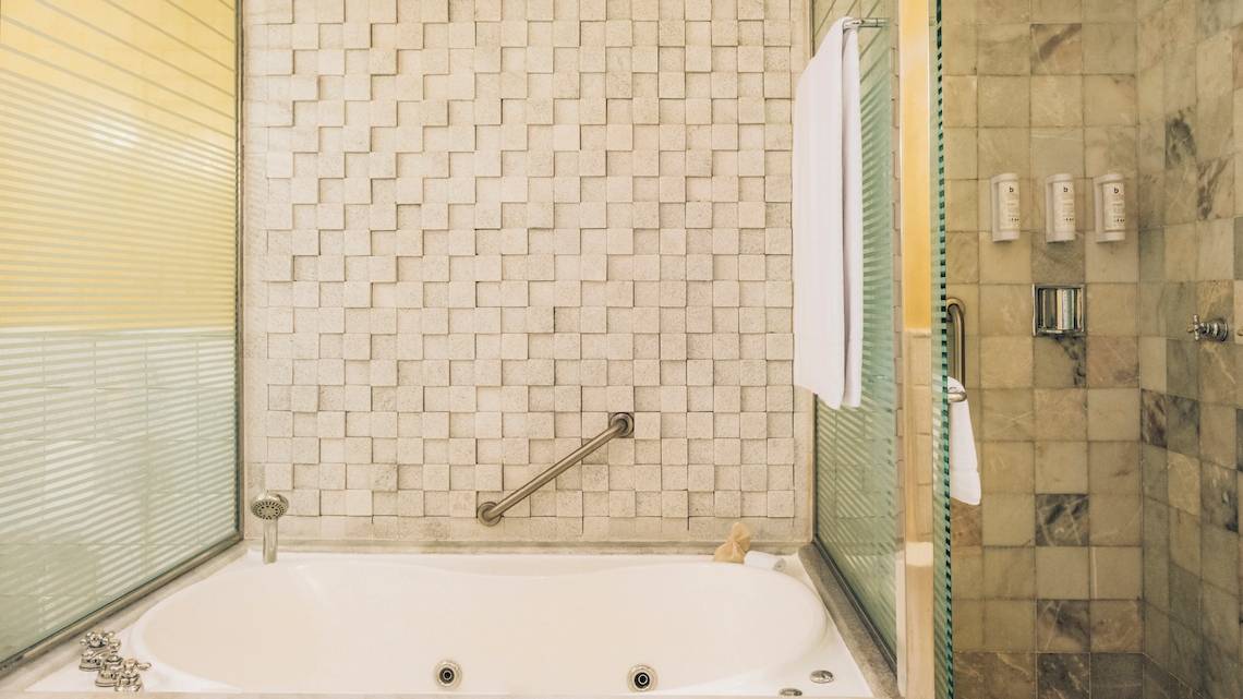 Badezimmer im Iberostar Grand Paraiso mit Badewanne, Handläufen und Fliesenwänden.
