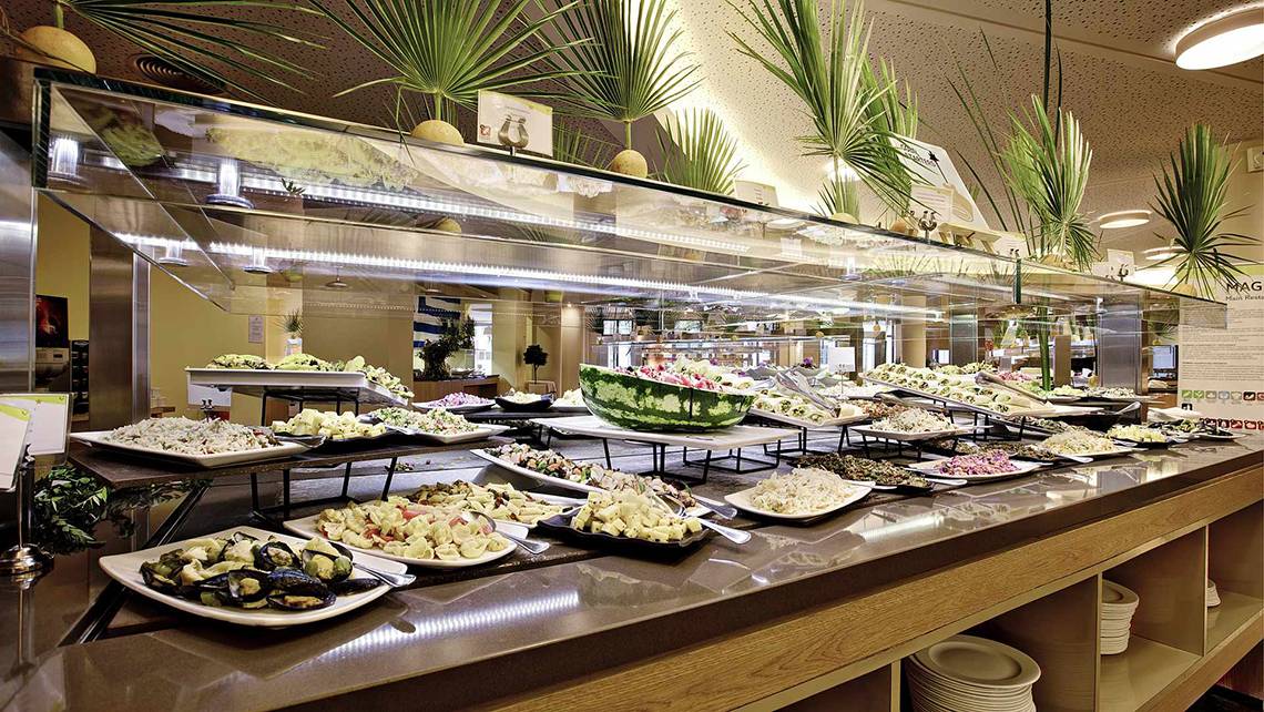 Buffet-Tisch im Club Plimmiri Hotel mit vielen verschiedenen Gerichten auf weißen Tellern.