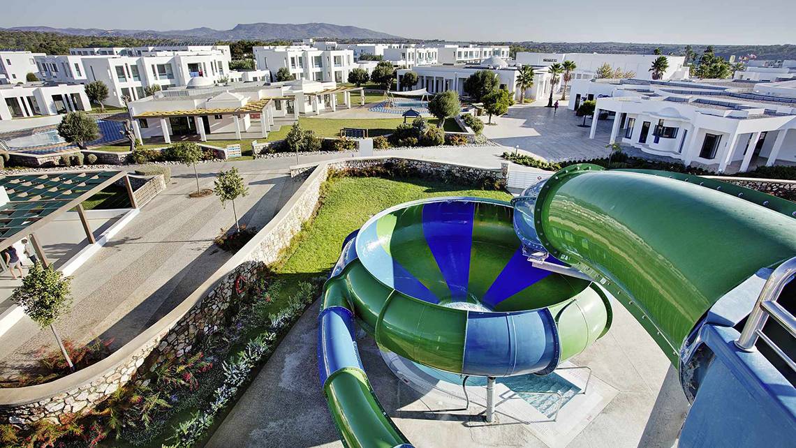 Luftaufnahme des Club Plimmiri Hotels mit einer großen Wasserrutsche im Vordergrund.
