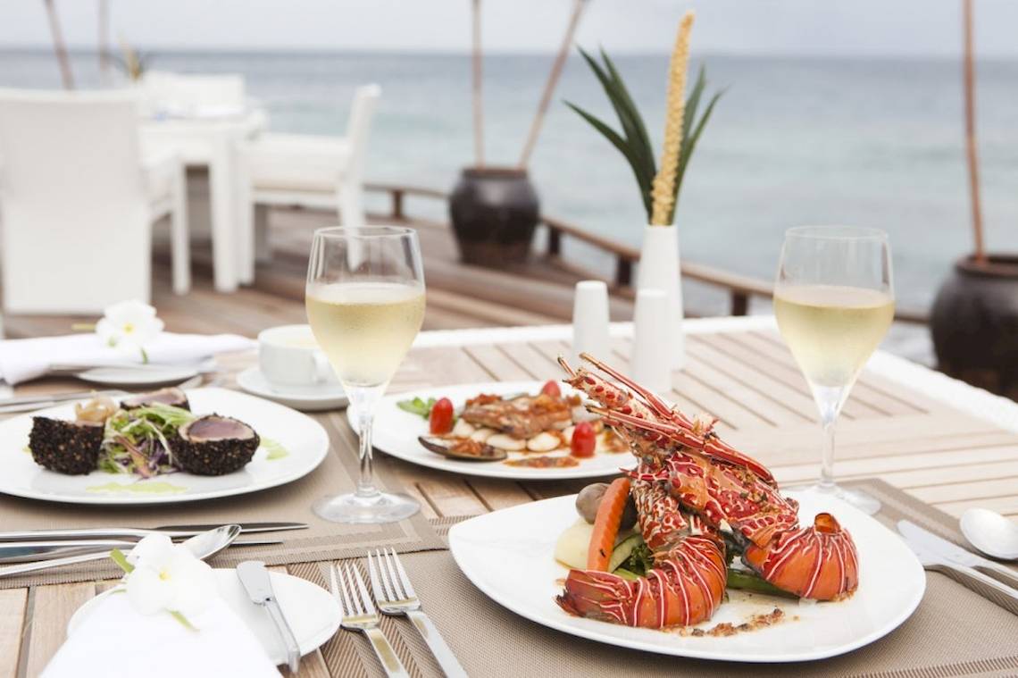 Essen am Tisch im Outrigger Maldives Maafushivaru Resort mit Meeresblick.